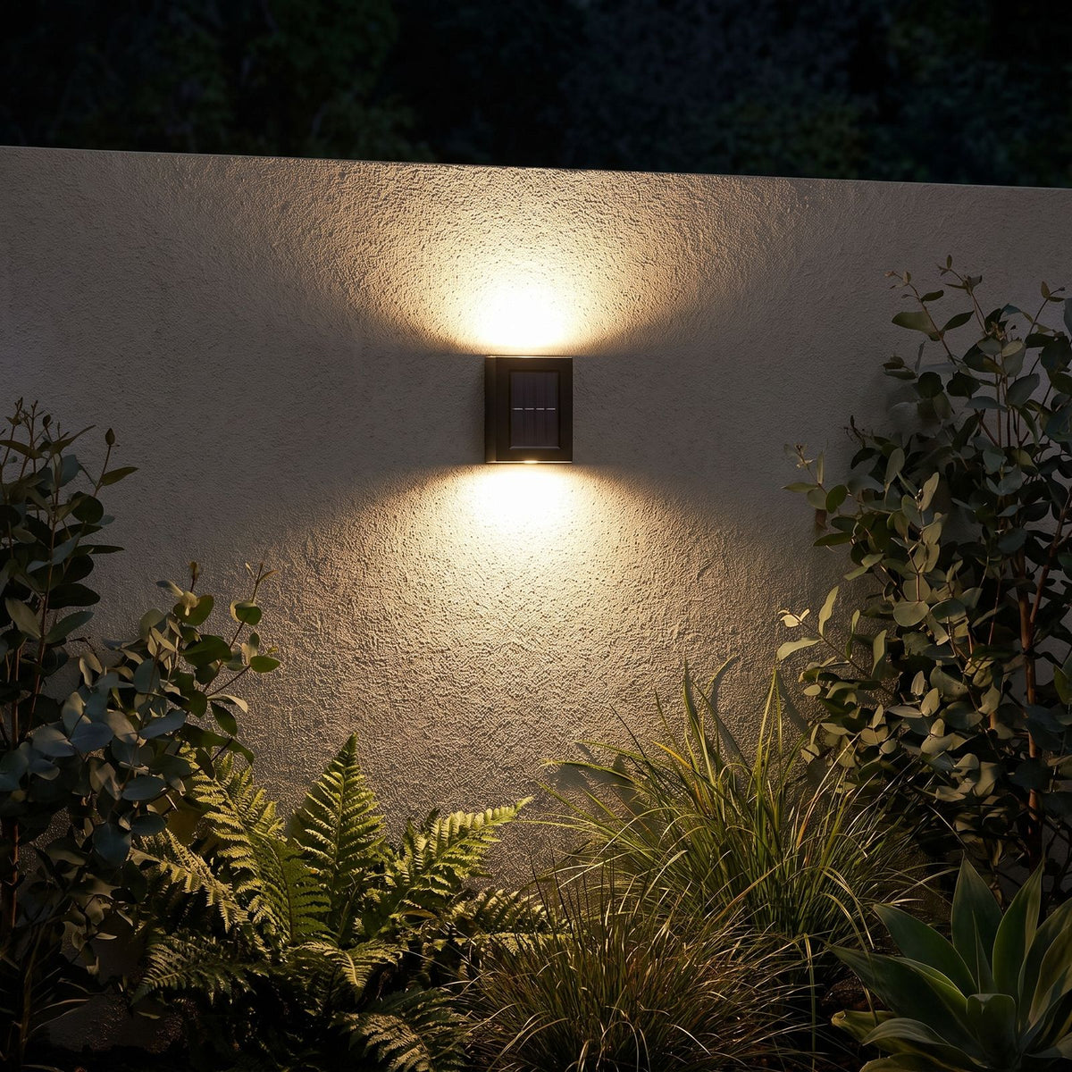 Solar Up Down Outdoor Wall Light glowing on a garden wall at night