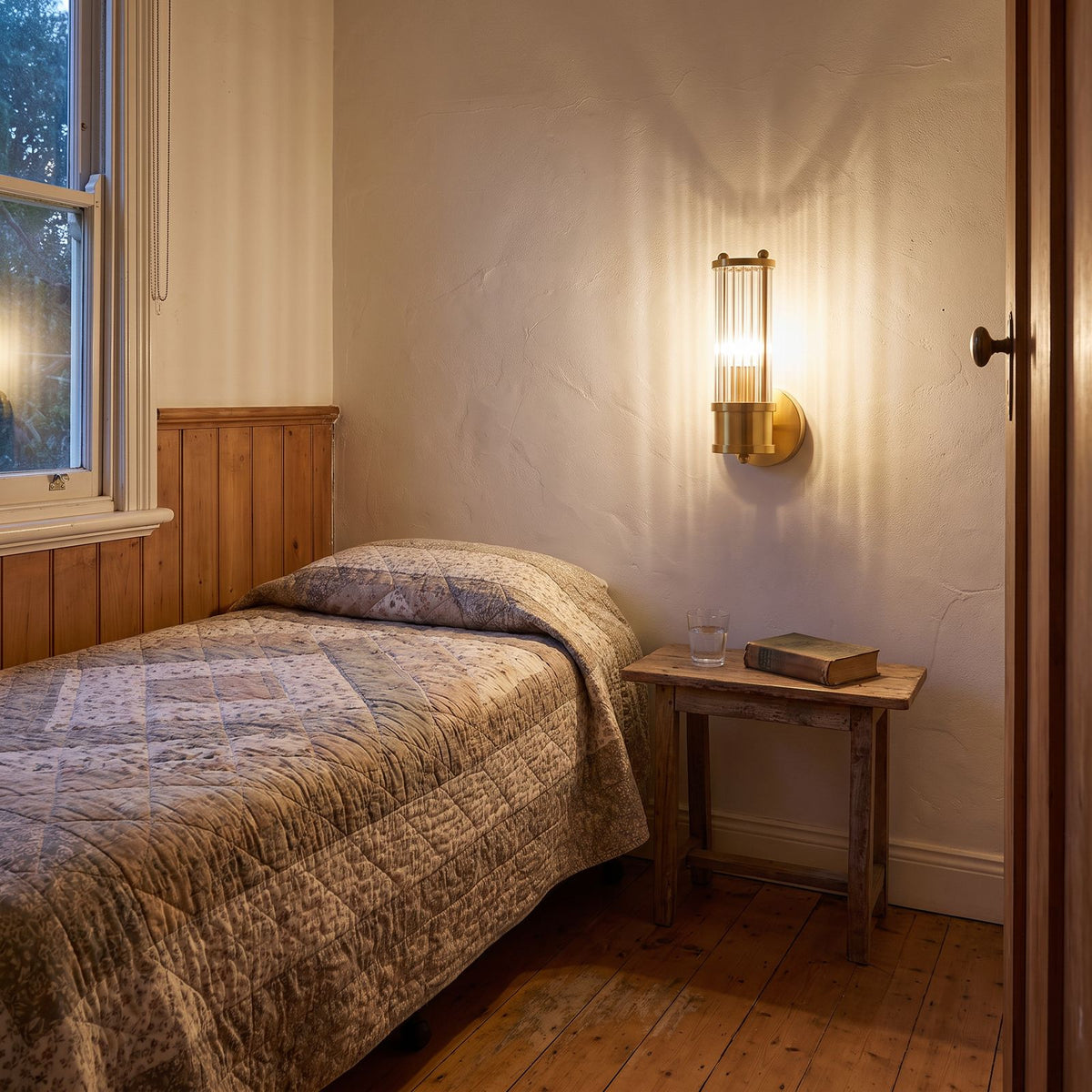 Ribbed Crystal Glass Tube Gold Wall Light with one tube above a small bedside table in a guest bedroom