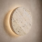 Solid Yellow Travertine Round LED Wall Light, close view at 45 degrees on a plaster wall