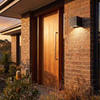 Square Adjustable Beam LED Outdoor Wall Light beside a timber front door
