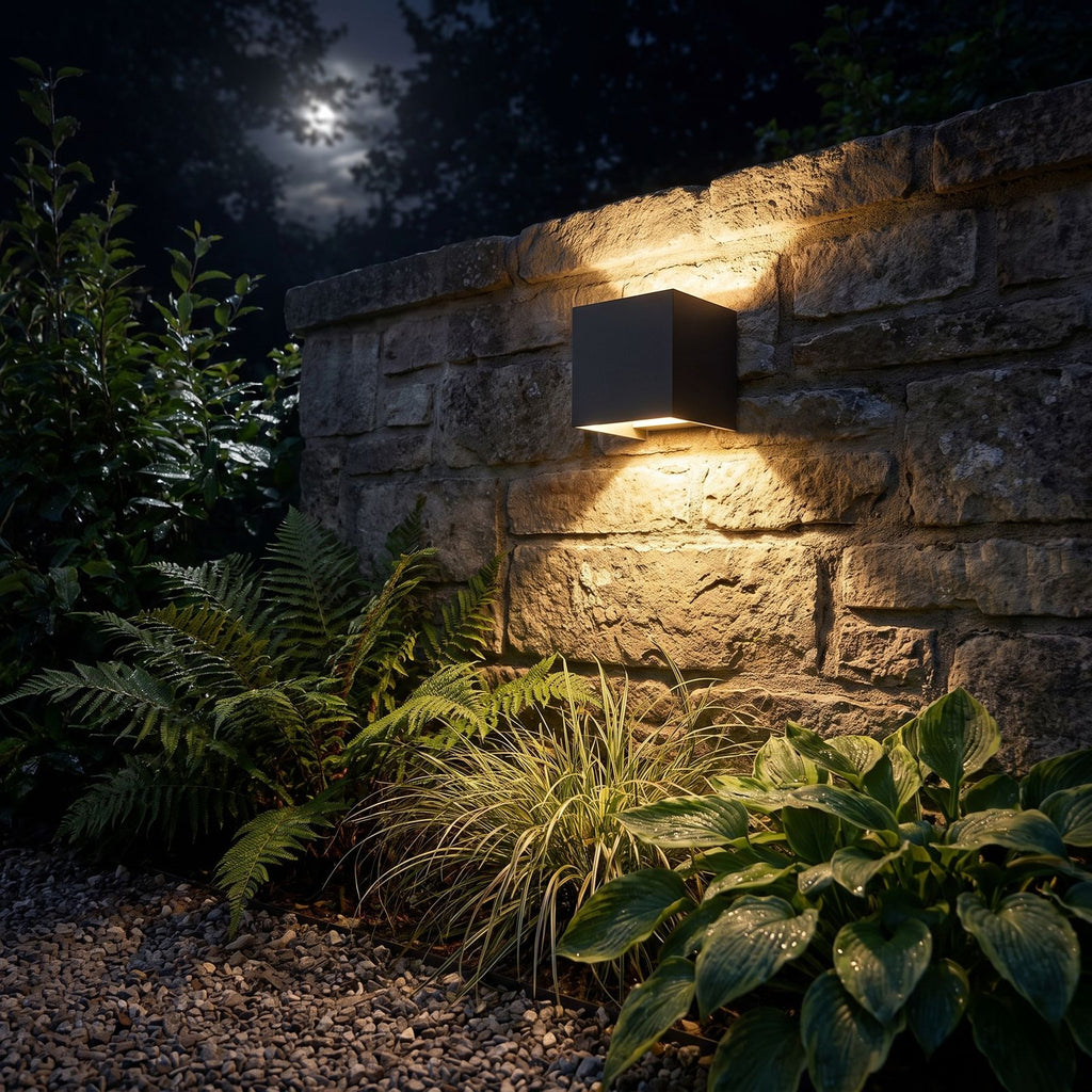 Square Adjustable Beam LED Outdoor Wall Light glowing on a garden wall at night