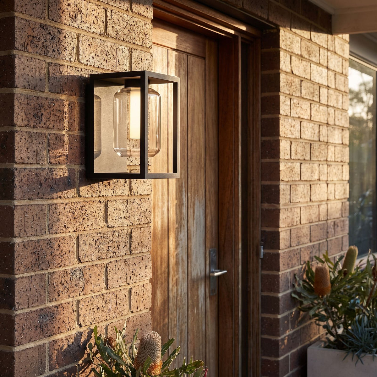 Square Frame Glass Outdoor Wall Lantern beside a timber front door