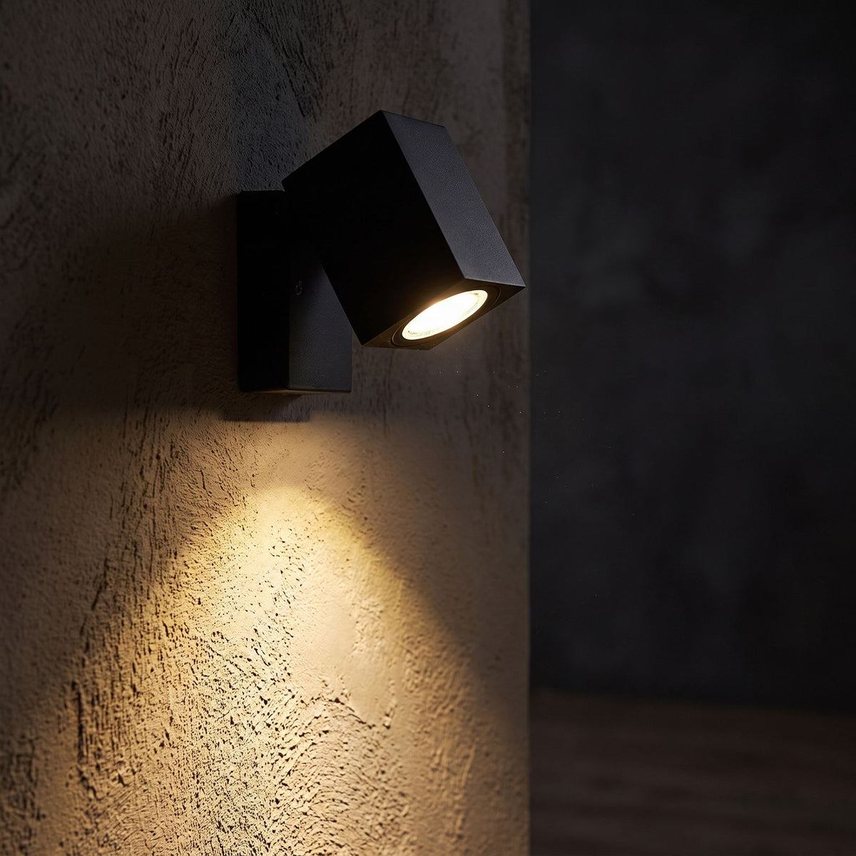 Square Head Rotatable Metal Spotlight Wall Light glowing on a plaster wall at night