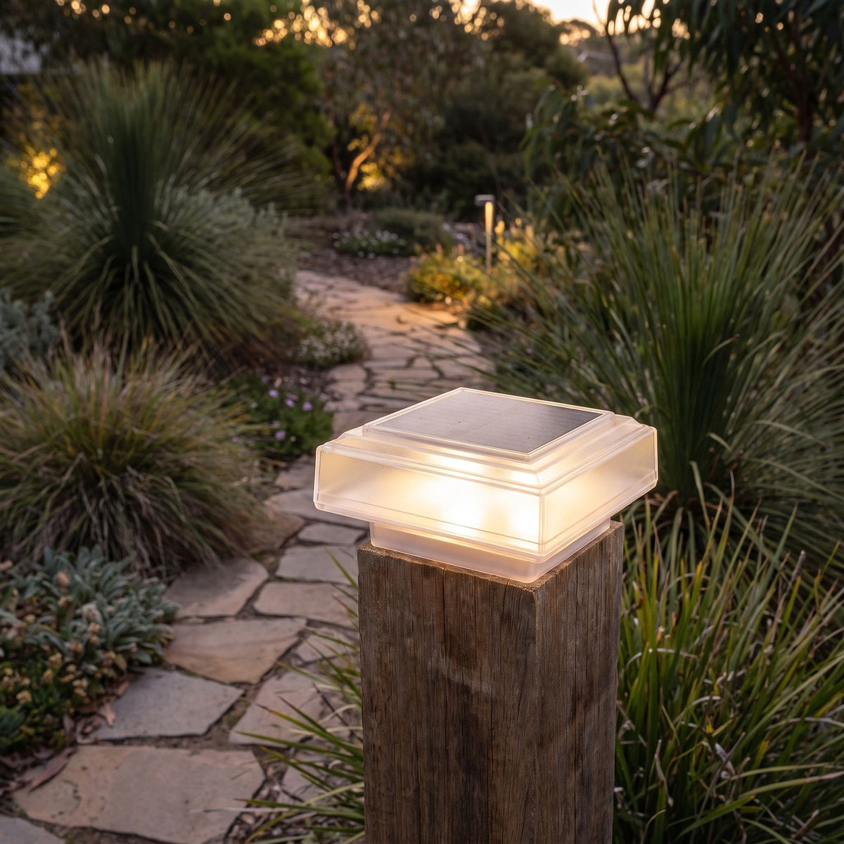 Square solar post cap light on a gate post beside a garden path
