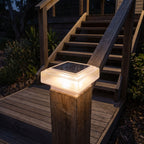 Square solar post cap light on a deck stair post at night