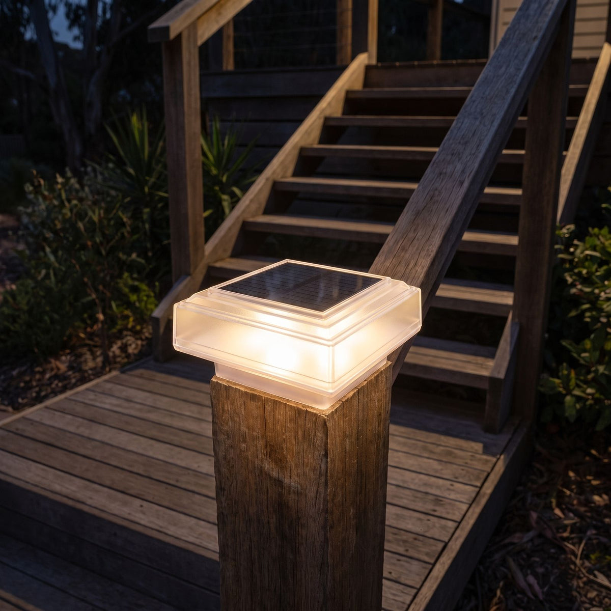 Square solar post cap light on a deck stair post at night