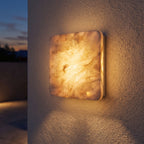 Square Travertine Stone LED Outdoor Wall Light on a porch wall at dusk