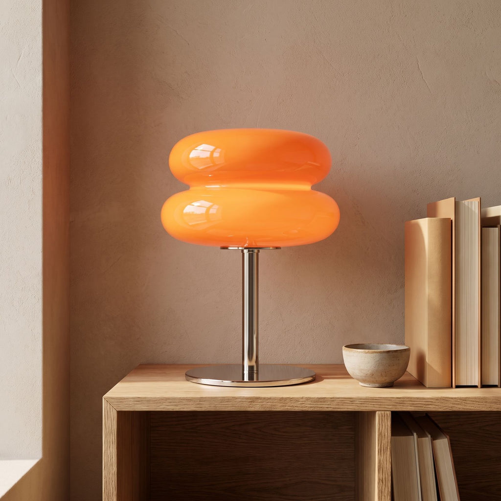 Orange stacked bubble table lamp on an oak shelf beside books