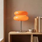Orange stacked bubble table lamp on an oak shelf beside books