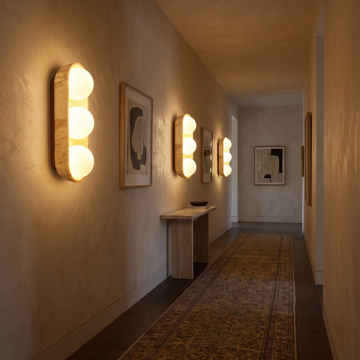 Three Stacked Frosted Globe Travertine Wall Lights with 3 globes in a row along a hallway at night