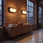A pair of Stacked Frosted Globe Travertine Wall Lights mounted horizontally above a walnut sideboard in a brick loft