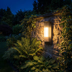 Striped Acrylic Cylinder Outdoor Wall Light glowing on a garden wall at night