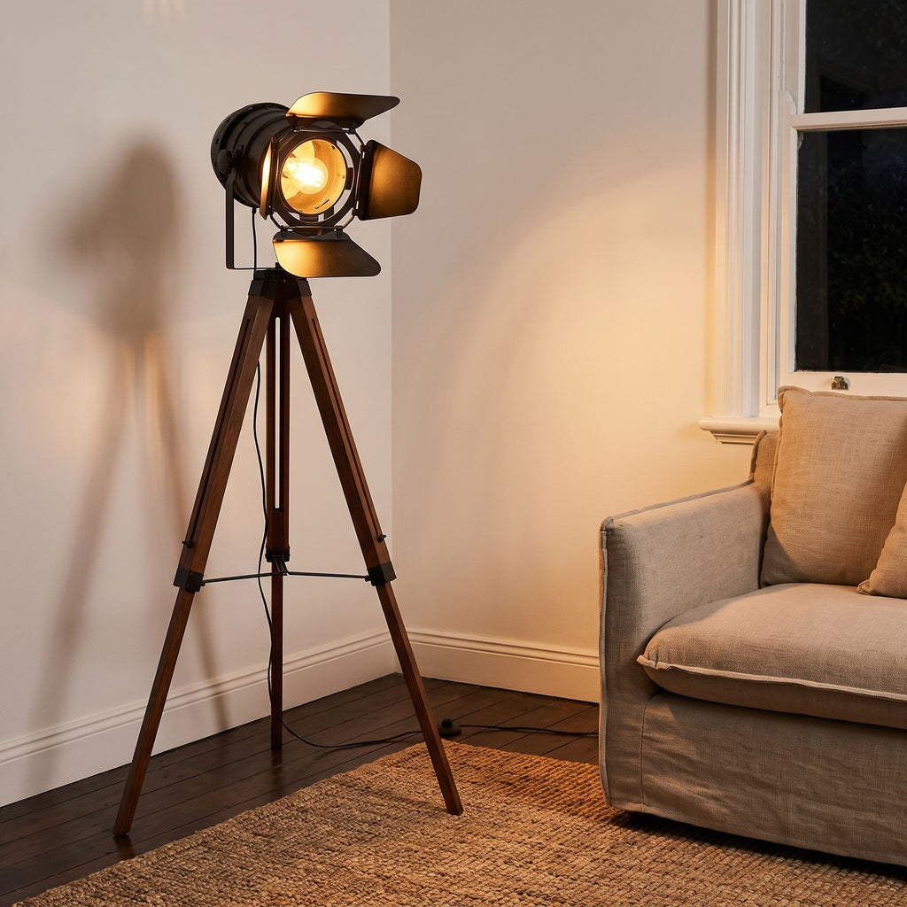 Studio Spotlight Wood Tripod Floor Lamp beside an armchair in a living room corner