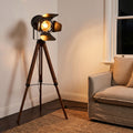 Studio Spotlight Wood Tripod Floor Lamp beside an armchair in a living room corner