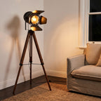 Studio Spotlight Wood Tripod Floor Lamp beside an armchair in a living room corner