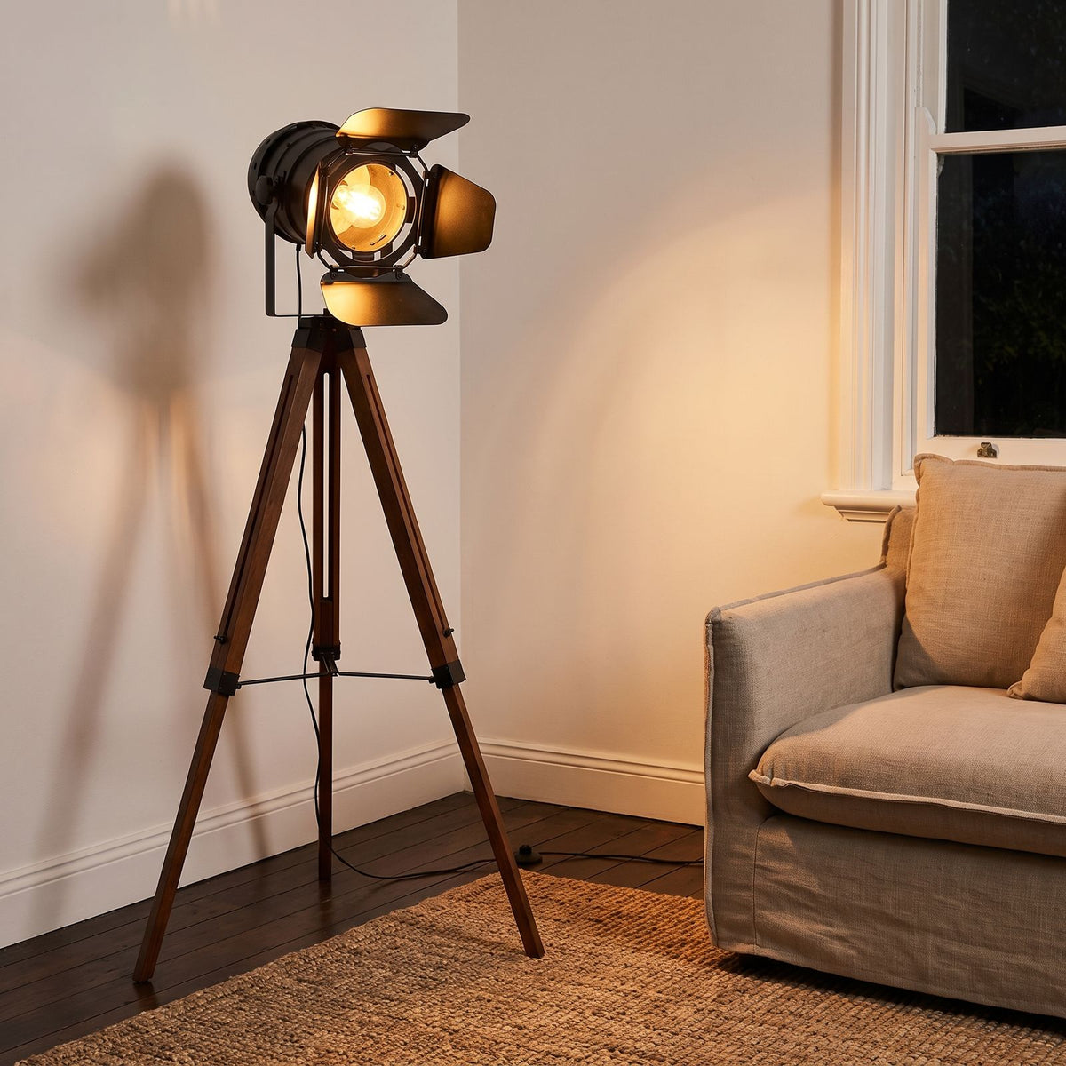 Studio Spotlight Wood Tripod Floor Lamp beside an armchair in a living room corner