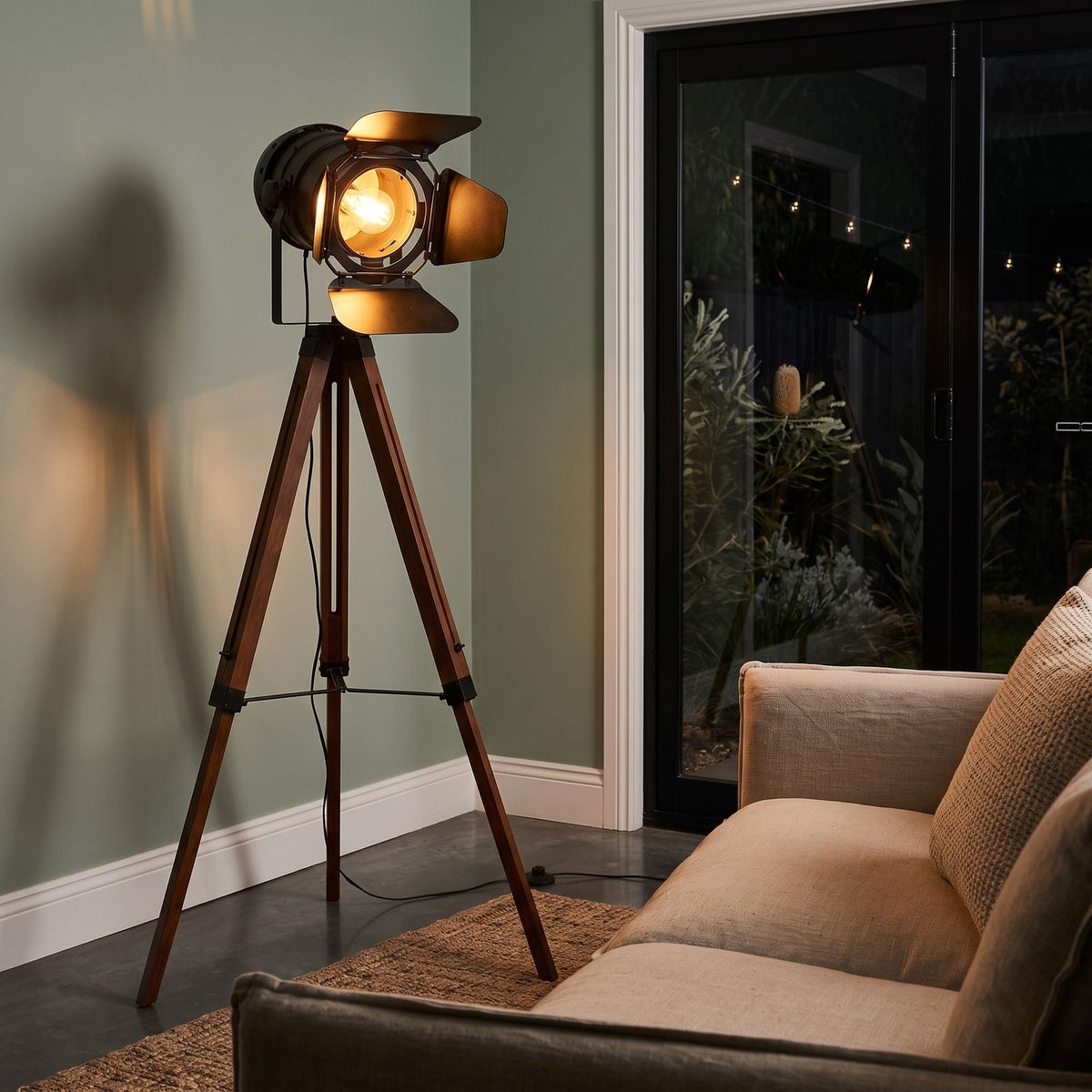 Studio spotlight tripod floor lamp behind a sofa at night