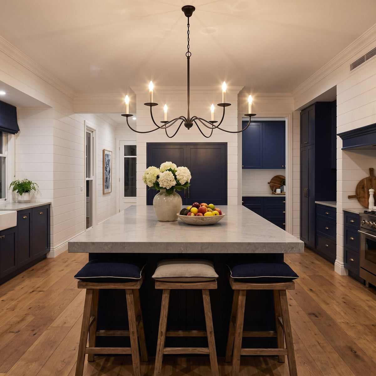 Sweeping Curved Arm Six Light Chandelier above a kitchen island at night