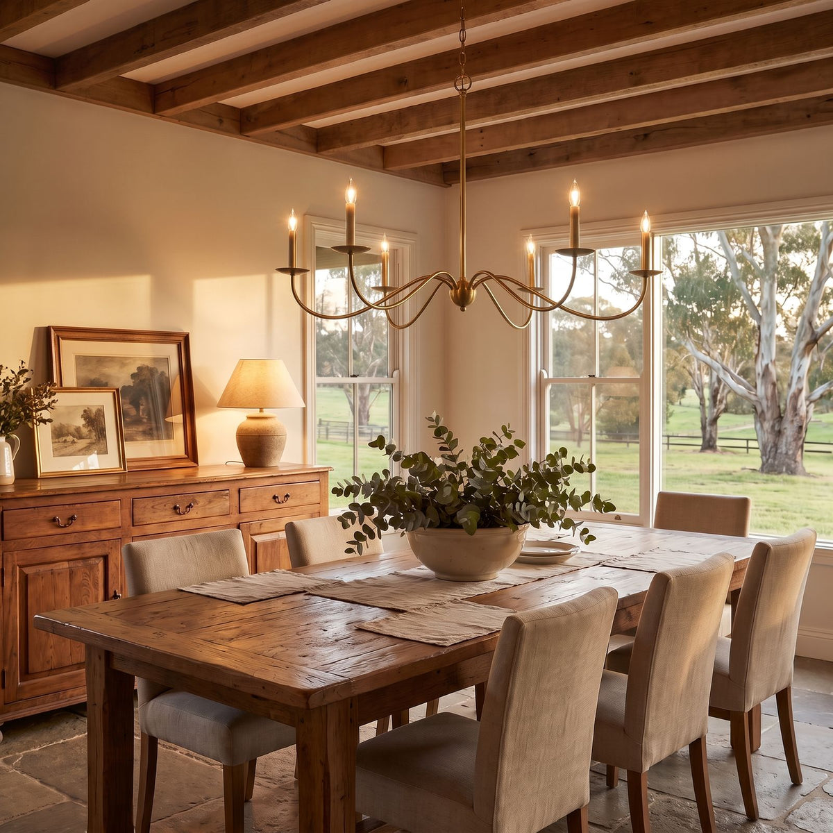 Sweeping Curved Arm Six Light Chandelier in brass above a dining table at golden hour