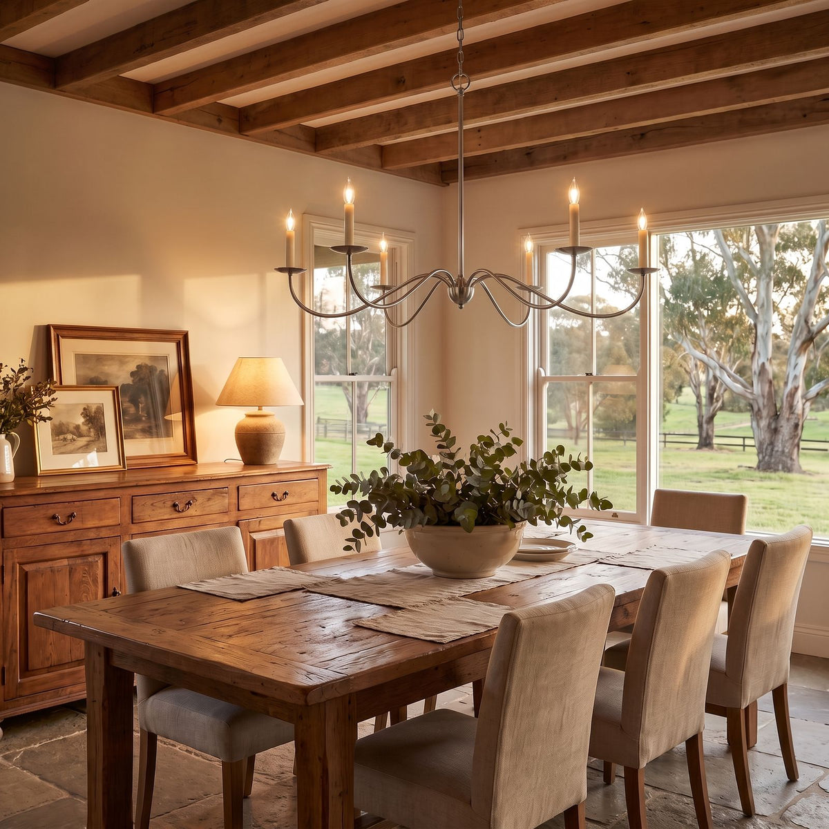 Sweeping Curved Arm Six Light Chandelier in nickel above a dining table at golden hour