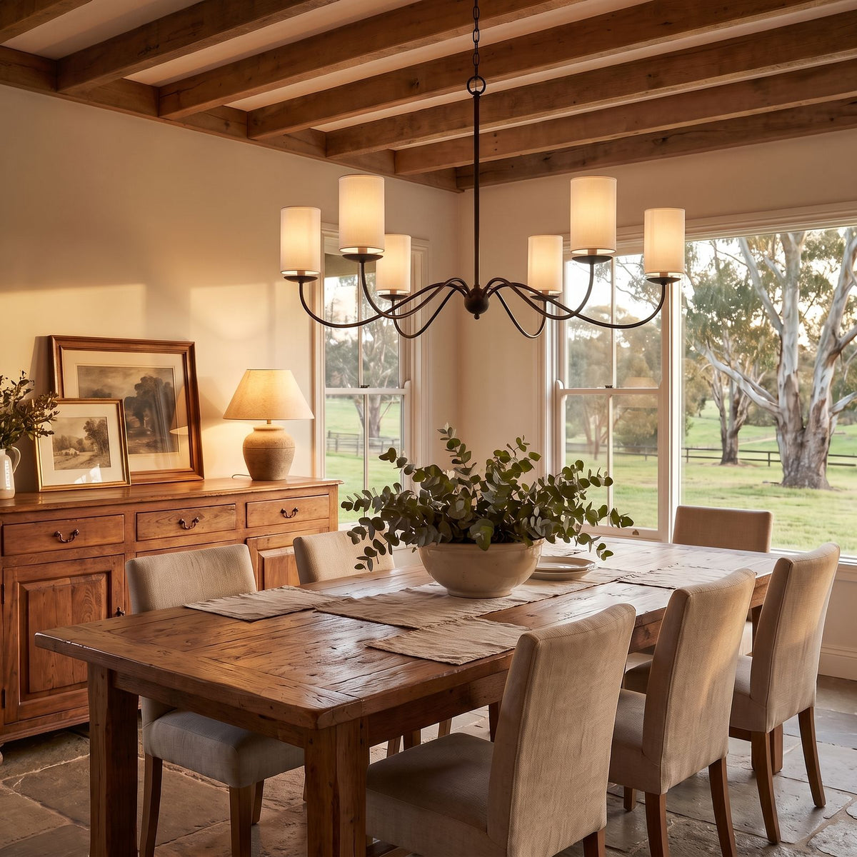 Sweeping Curved Arm Six Light Chandelier with shades above a dining table at golden hour