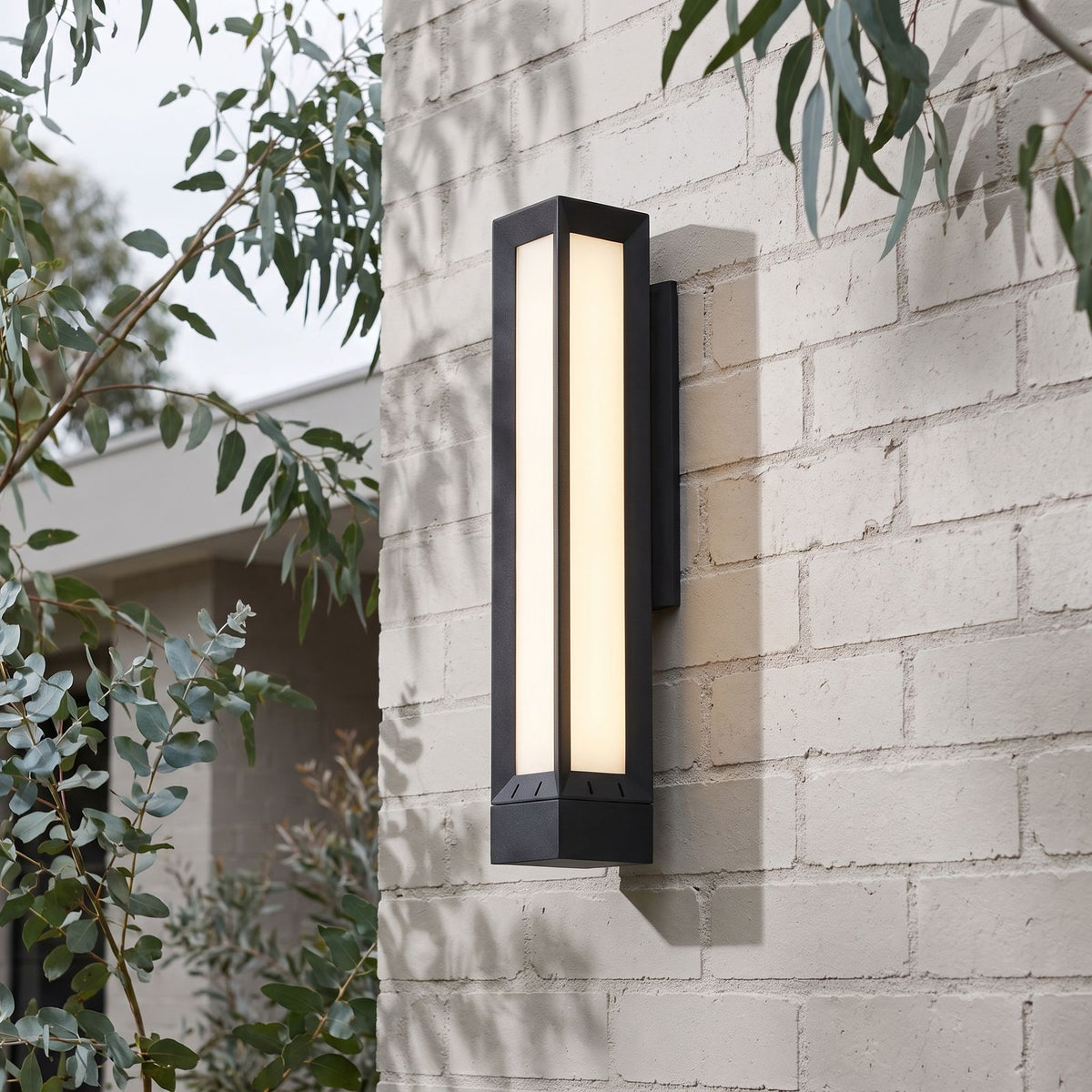 Tall Black Frame LED Outdoor Wall Light on a painted brick wall, angled view