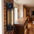 Tall Black Iron Flute Edison Wall Light on a bedroom wall beside the bed