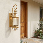 Tall Brass and Clear Glass Outdoor Wall Lantern beside a timber front door