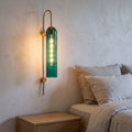 Tall Hook Arm Glass Cylinder Wall Light beside a bed