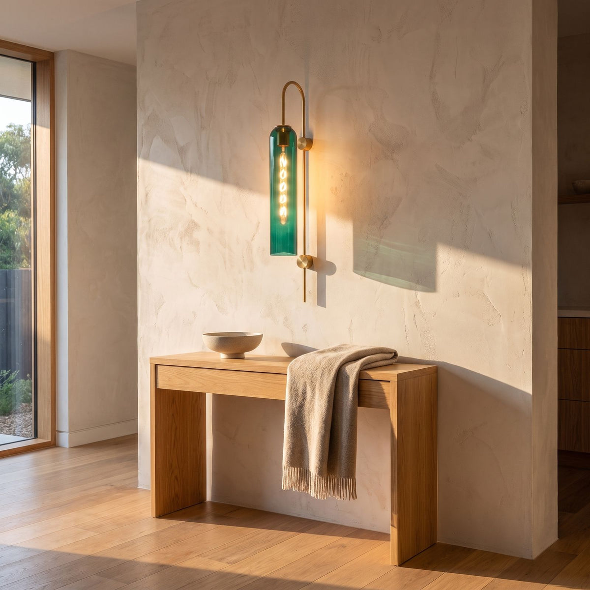 Tall hook arm glass cylinder wall light in a wide entry hall view