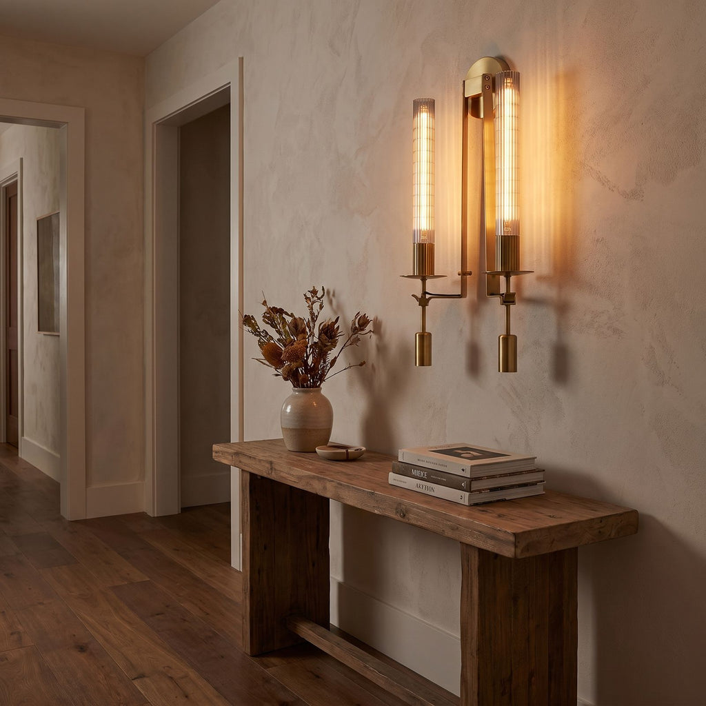 Tall Ribbed Glass and Brass Column Wall Light in a hallway above a timber console