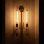 Tall Ribbed Glass and Brass Column Wall Light glowing on a plaster wall at night