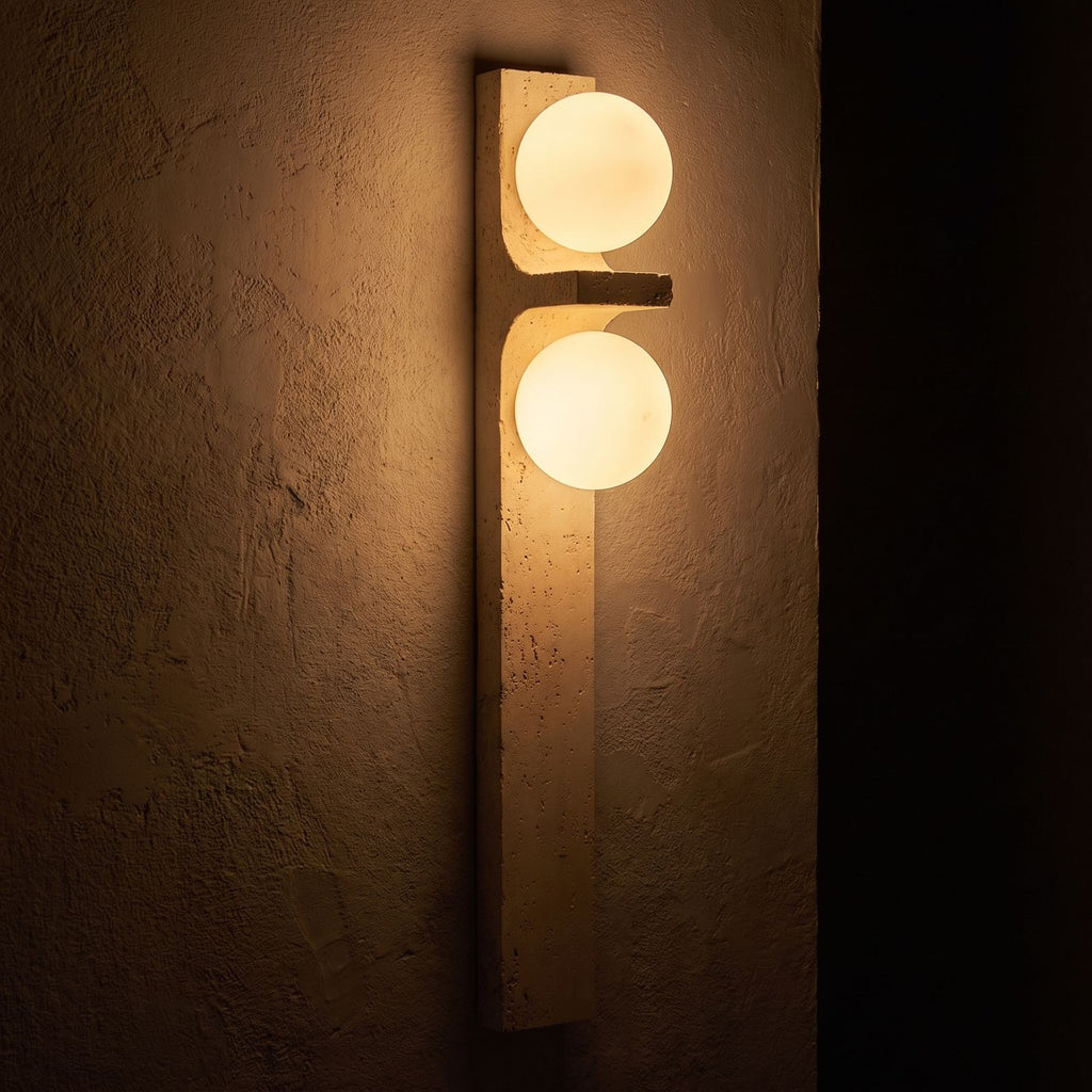 Tall Slim Travertine Strip Wall Light glowing on a plaster wall at night