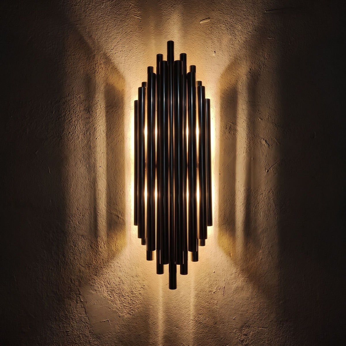 Tall Stainless Steel Up and Down Wall Light glowing on a plaster wall at night