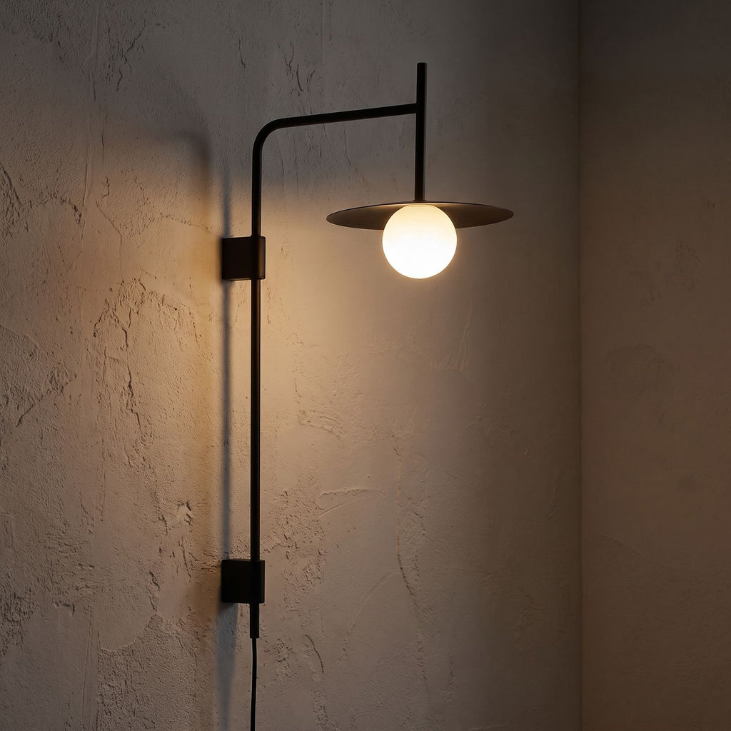 Tall Swing Arm Globe Plug-In Wall Light glowing on a plaster wall at night