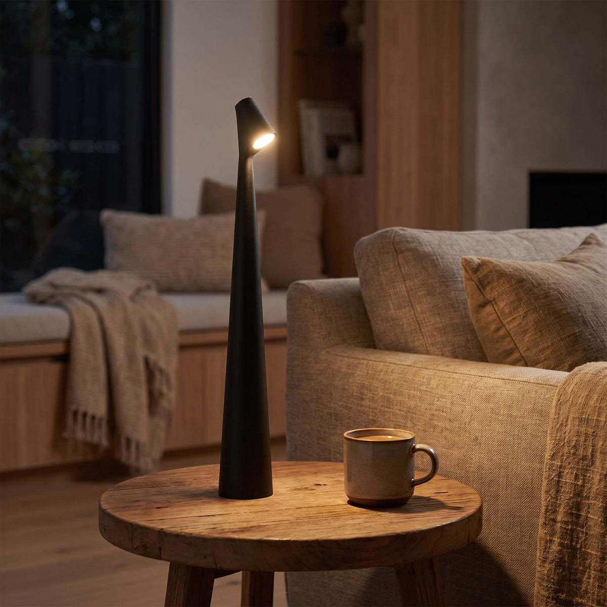 Tall tapered rechargeable table lamp on a side table beside a sofa