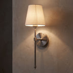 Tapered Fabric Shade Wireless Wall Sconce glowing on a plaster wall at night