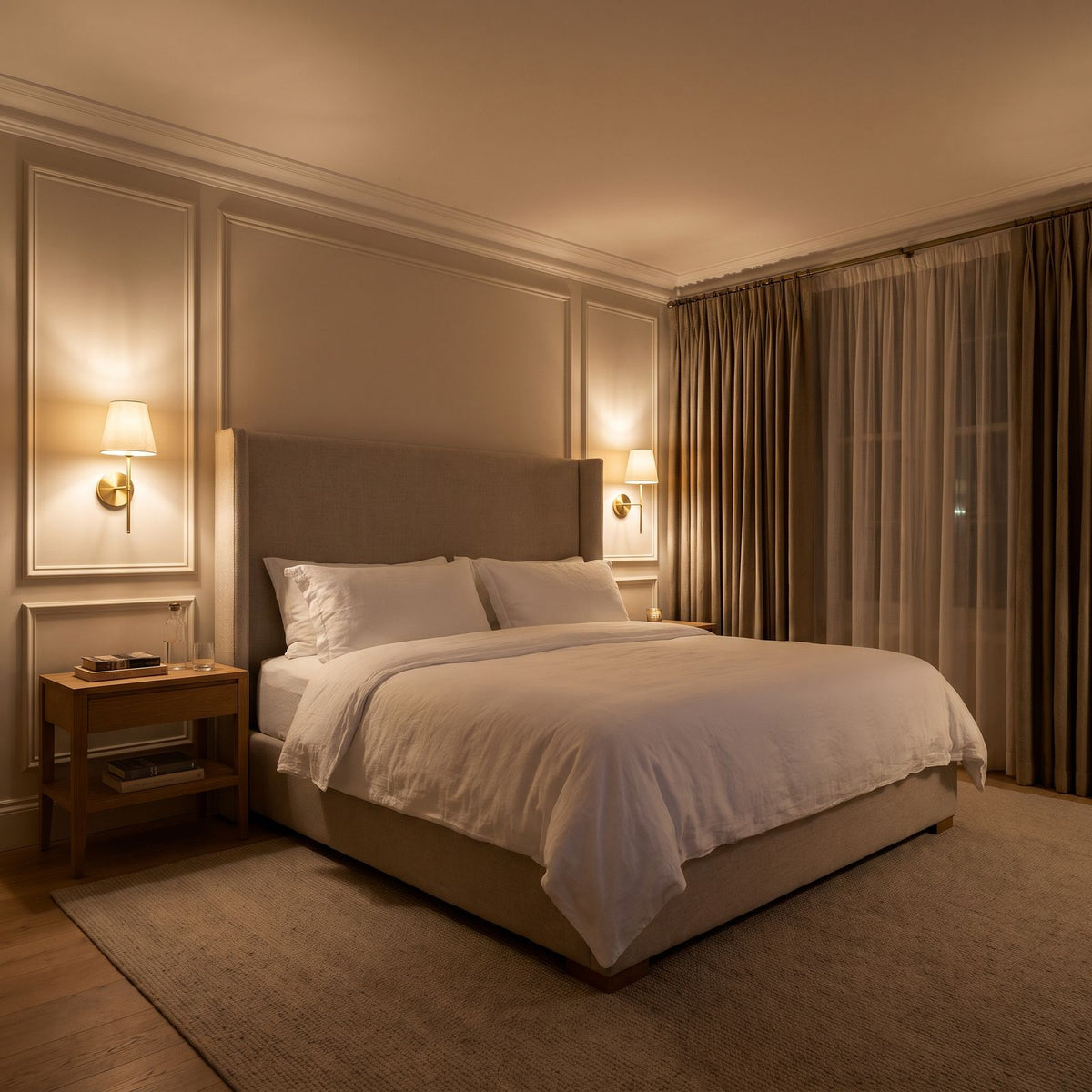 A pair of the wireless wall sconces in gold, one on each side of the bed in a bedroom at night