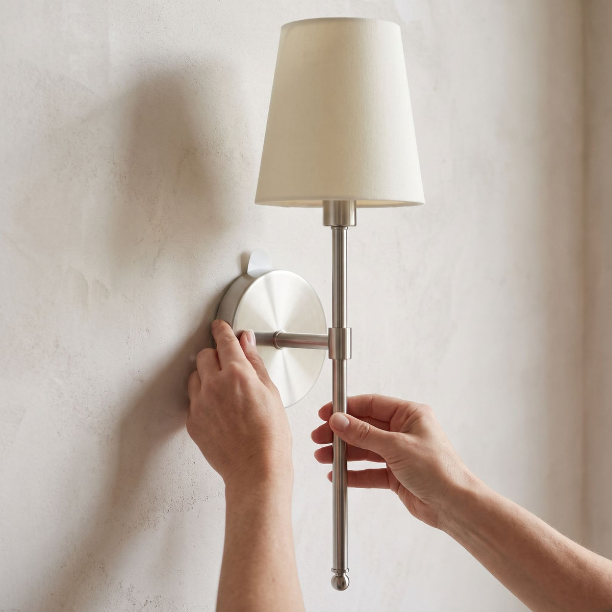 The round wall plate of the wireless wall sconce pressed onto the wall with its adhesive pad, no wiring