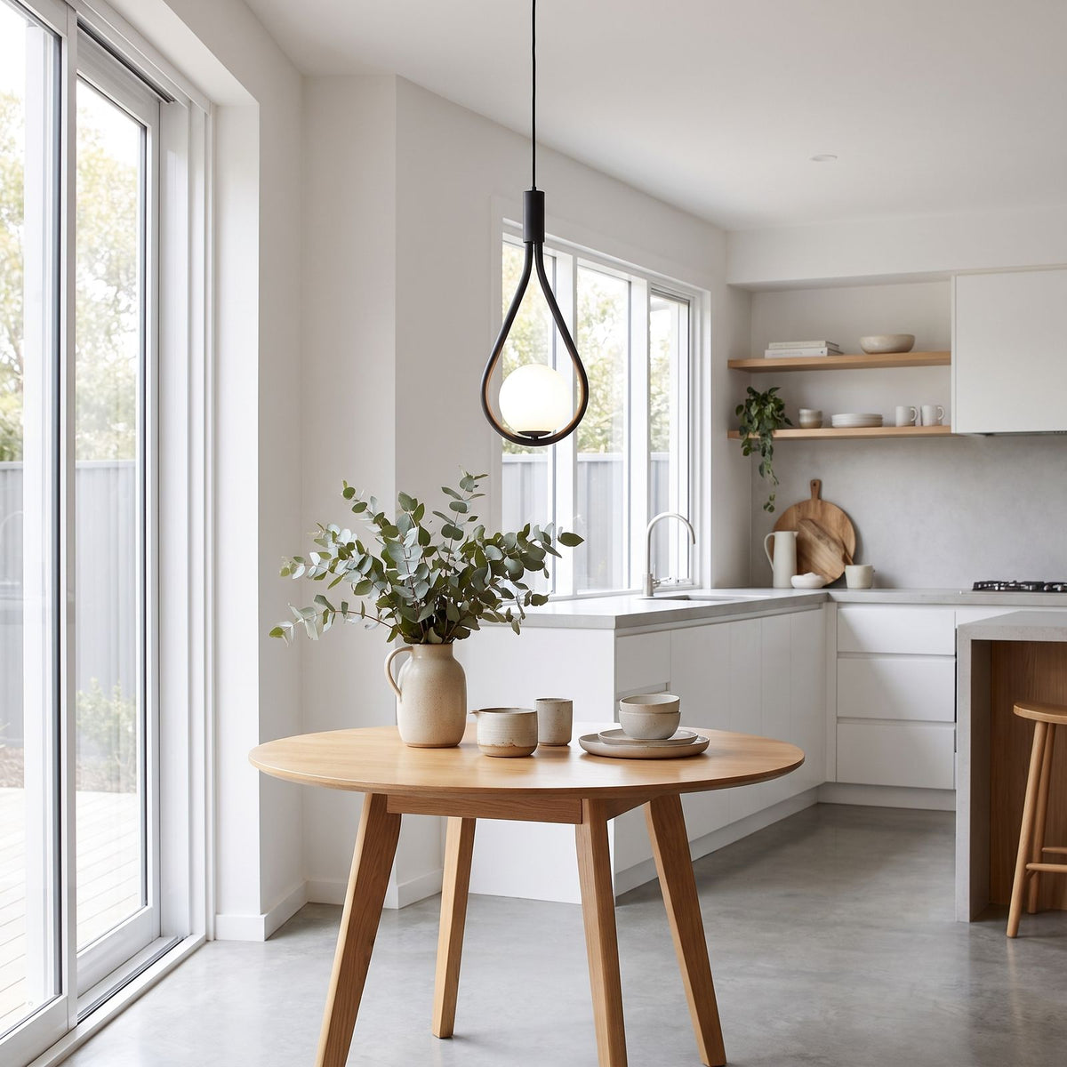 Teardrop frame glass globe pendant light over a small kitchen table in daylight
