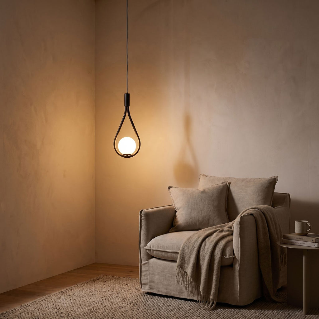 Teardrop frame glass globe pendant light over a reading armchair at night