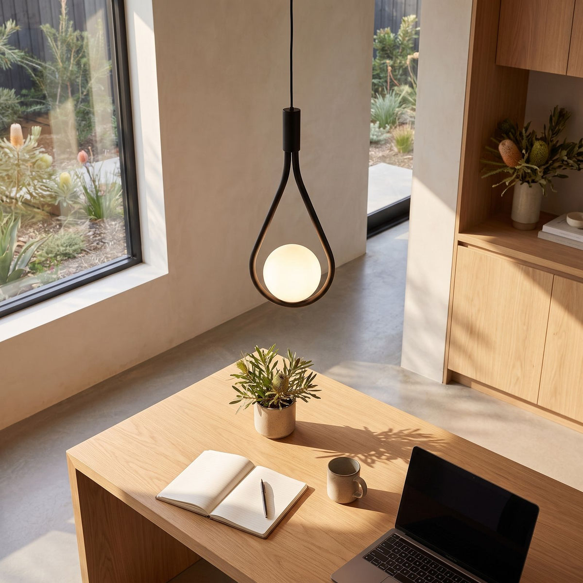 Teardrop frame glass globe pendant light above a home office desk in daylight