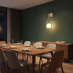 Teardrop Gold Frame Opal Glass Globe Wall Light on a green dining room wall beside a sideboard at night