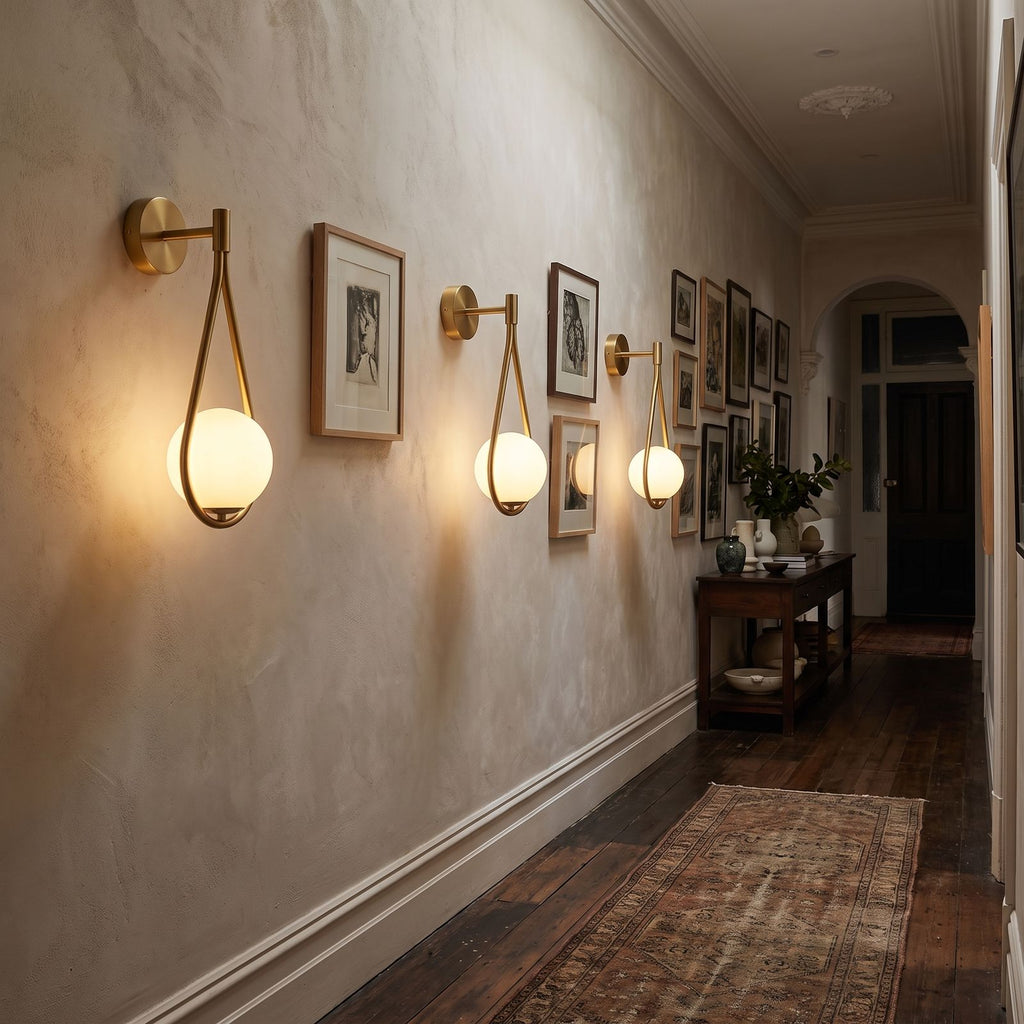 Teardrop Gold Frame Opal Glass Globe Wall Light three in a row along a heritage hallway at night