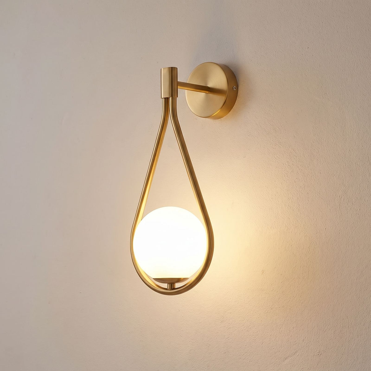Teardrop Gold Frame Opal Glass Globe Wall Light close view of the gold teardrop frame and opal glass globe, switched on