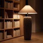Textured clay base cone shade floor lamp in a reading corner at night
