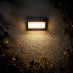 Three Mode Solar Outdoor Wall Light glowing on a garden wall at night