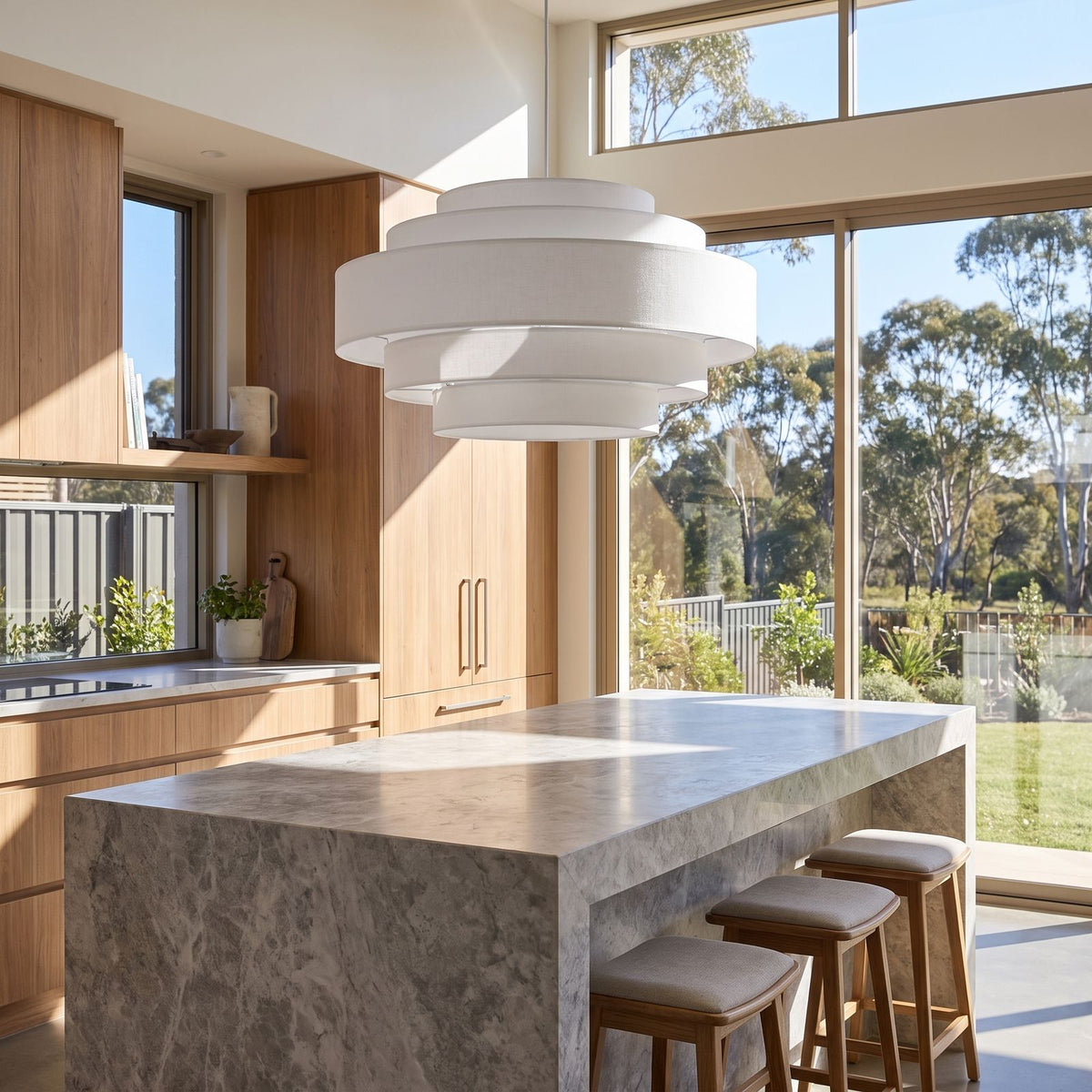 Tiered white drum LED pendant light over a kitchen island in daylight