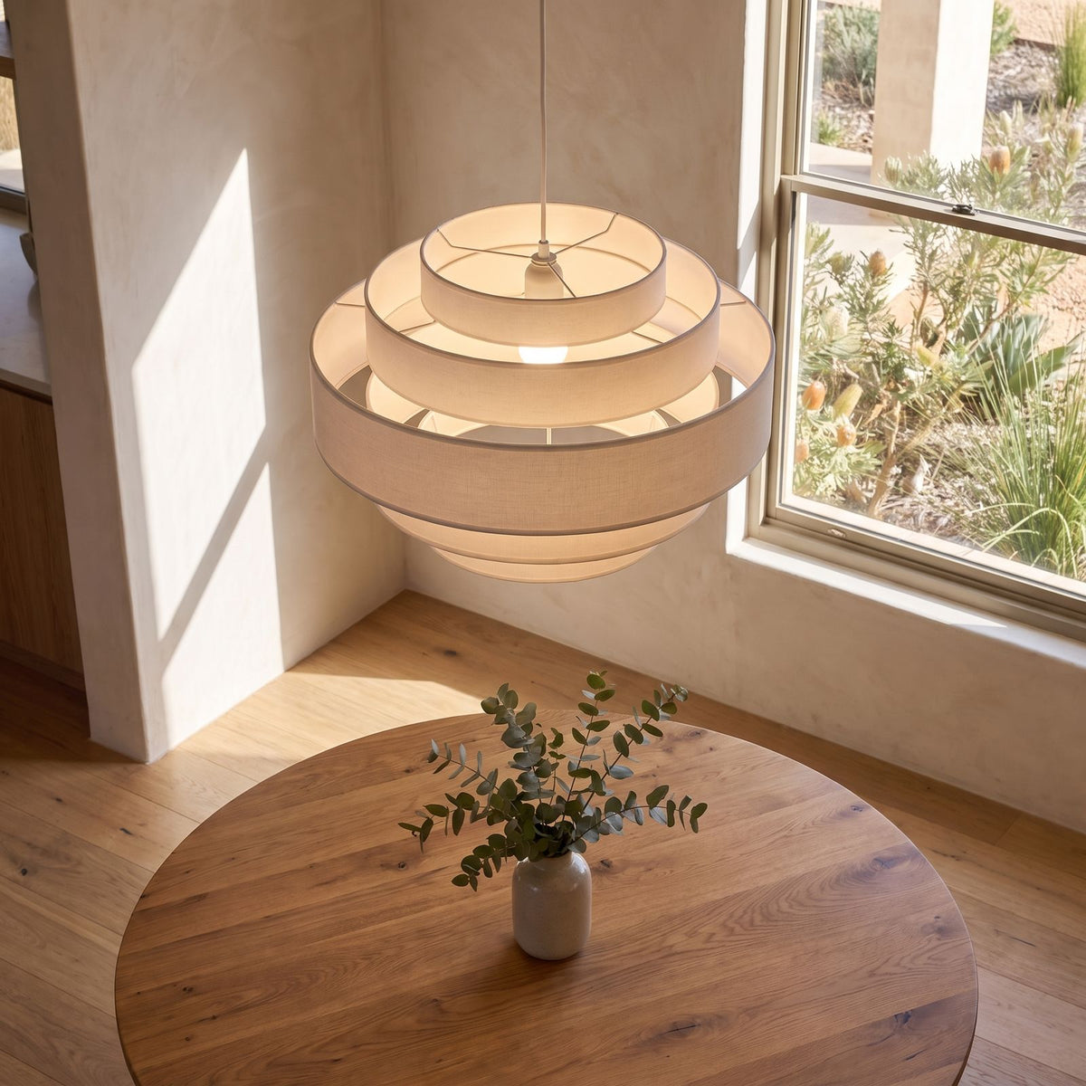 Tiered white drum LED pendant light in an entry hall in daylight