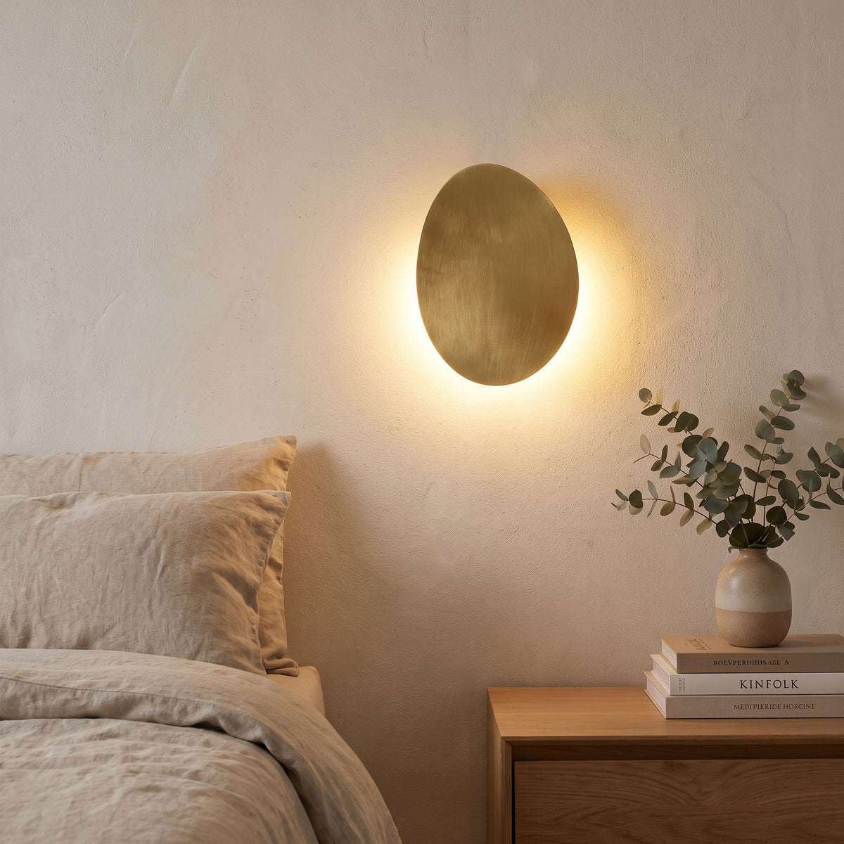 Tilted Pebble Aluminium Backlit LED Wall Light beside a bed